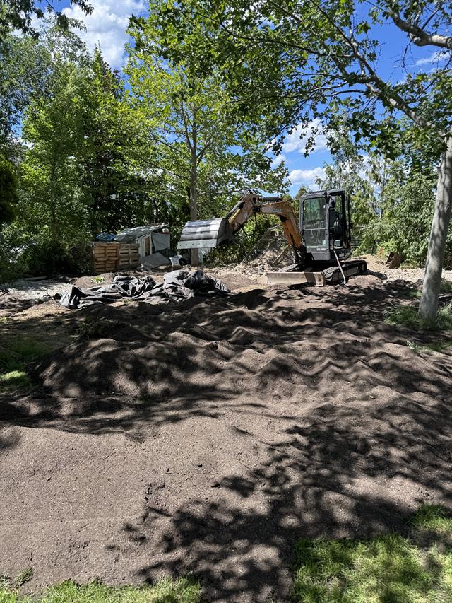 Excavator grading and preparing a yard for landscaping